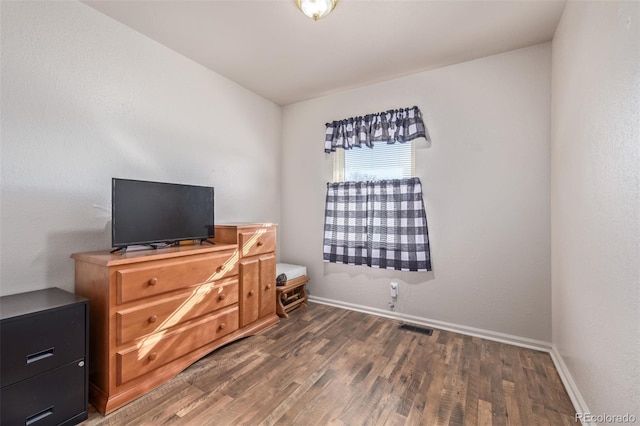 bedroom with baseboards, visible vents, and wood finished floors