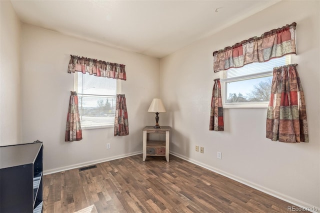 unfurnished room featuring visible vents, baseboards, and wood finished floors