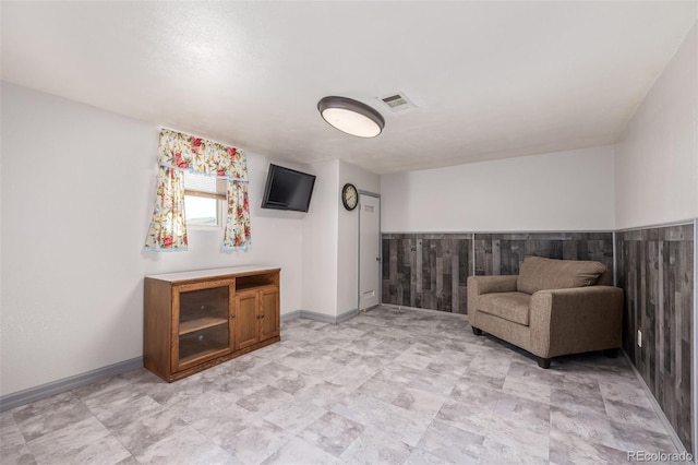 unfurnished room featuring a wainscoted wall, baseboards, and visible vents