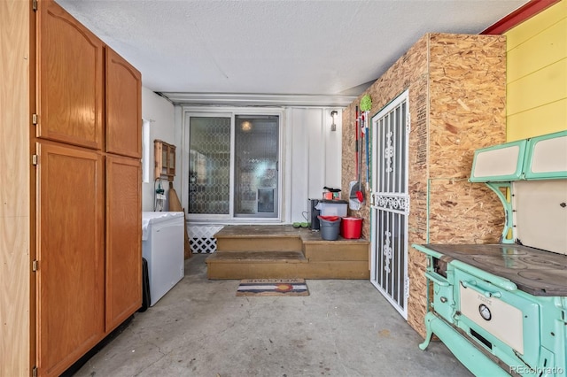 interior space featuring a textured ceiling, washer / clothes dryer, and concrete floors