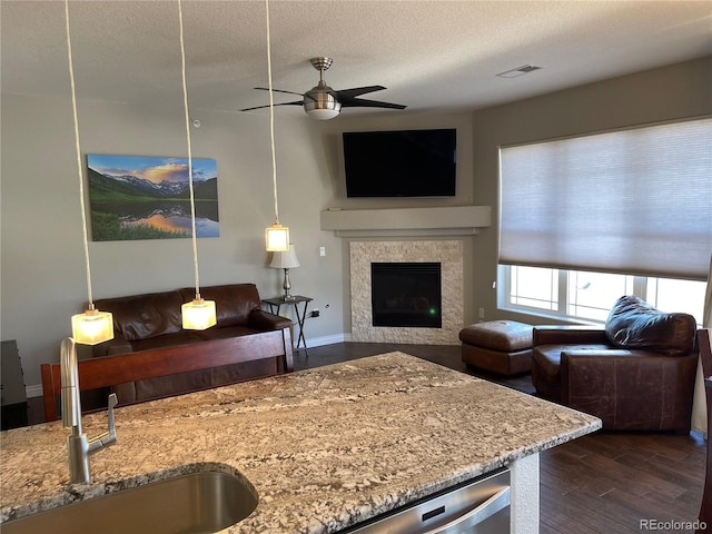 9557 W San Juan Cir Unit 207, Littleton, CO 80128 - living room featuring a ceiling fan, dark wood-style floors, a fireplace, and a textured ceiling
