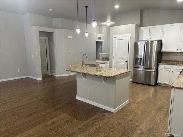 kitchen featuring white cabinets, pendant lighting, sink, stainless steel refrigerator with ice dispenser, and light stone countertops