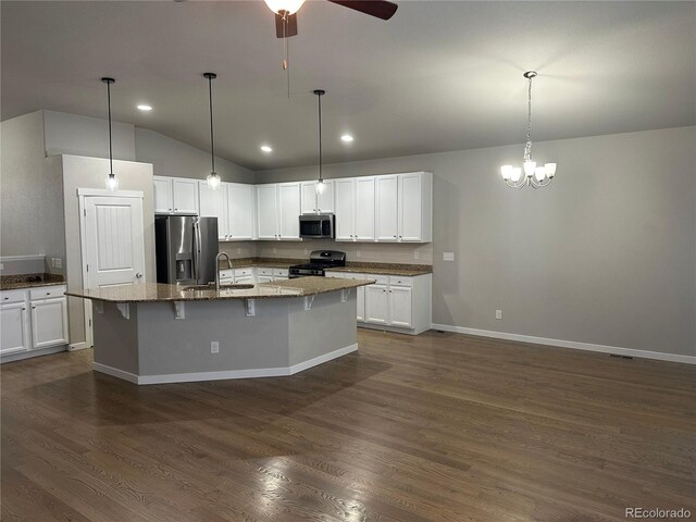 kitchen with ceiling fan with notable chandelier, dark hardwood / wood-style flooring, stainless steel appliances, stone counters, and a kitchen island with sink