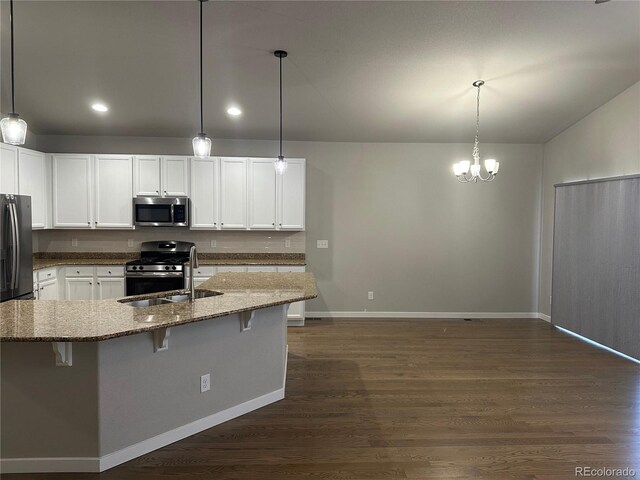 kitchen with white cabinets, pendant lighting, appliances with stainless steel finishes, a kitchen breakfast bar, and dark hardwood / wood-style flooring