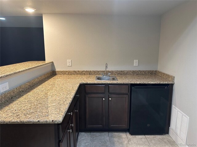 kitchen featuring light stone counters, black dishwasher, sink, kitchen peninsula, and light tile patterned floors