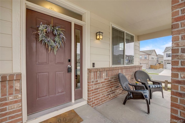 doorway to property featuring covered porch and brick siding