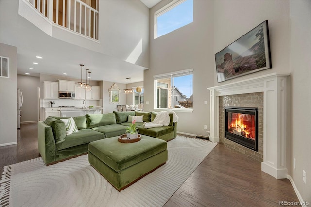 living area featuring baseboards, dark wood finished floors, a high ceiling, and a fireplace