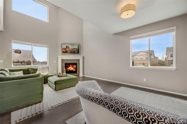 living room with baseboards, visible vents, a tiled fireplace, and dark wood-type flooring
