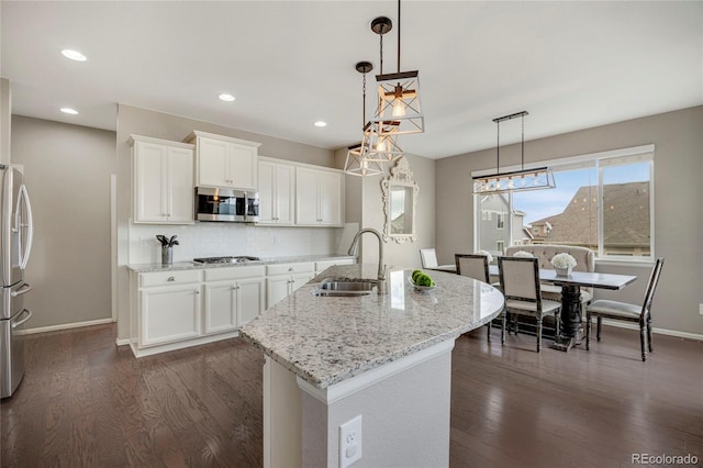 kitchen featuring a sink, baseboards, dark wood-style floors, stainless steel appliances, and white cabinetry