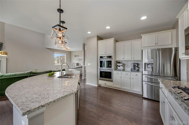 kitchen featuring dark wood-style flooring, white cabinetry, light stone counters, a sink, and stainless steel appliances