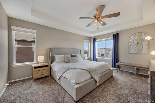 carpeted bedroom featuring baseboards, a ceiling fan, and a raised ceiling