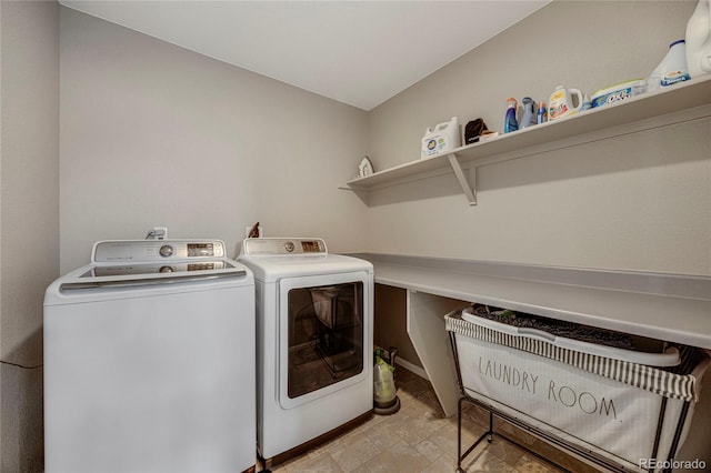 washroom with washer and dryer, laundry area, stone finish flooring, and baseboards