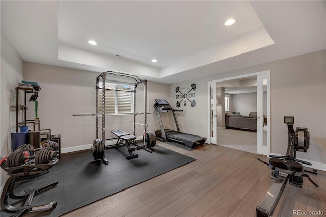 workout room with baseboards, a tray ceiling, recessed lighting, and wood finished floors