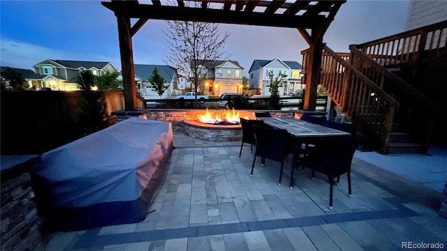 view of patio featuring a fire pit, fence, a pergola, stairway, and outdoor dining space