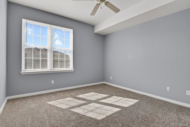 carpeted spare room with a ceiling fan and baseboards