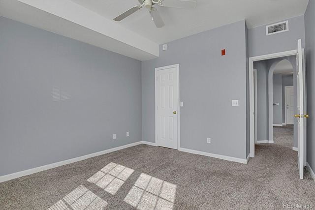 unfurnished bedroom with arched walkways, carpet flooring, visible vents, and baseboards