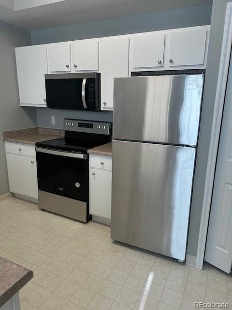 kitchen with stainless steel appliances, baseboards, white cabinets, light floors, and dark countertops