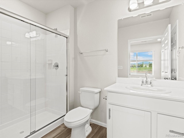 bathroom with hardwood / wood-style floors, toilet, a shower with door, and vanity