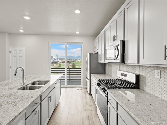 kitchen with tasteful backsplash, sink, white cabinetry, light stone countertops, and stainless steel appliances