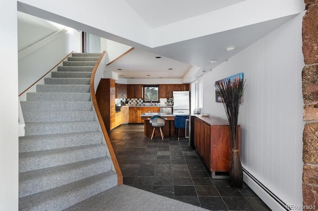 stairs featuring a baseboard heating unit and sink