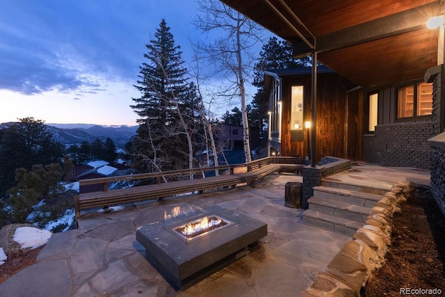 patio terrace at dusk featuring a mountain view and an outdoor fire pit