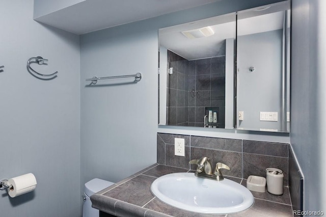 bathroom with vanity, toilet, and backsplash