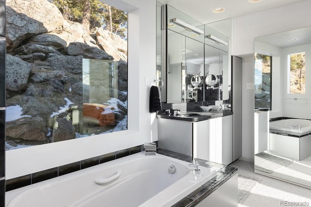 bathroom featuring a relaxing tiled tub and vanity