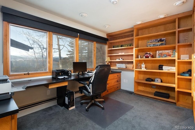 carpeted home office with a baseboard heating unit and built in desk