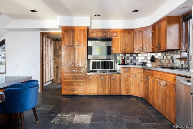 kitchen featuring light countertops, stone finish flooring, brown cabinets, tasteful backsplash, and stainless steel dishwasher