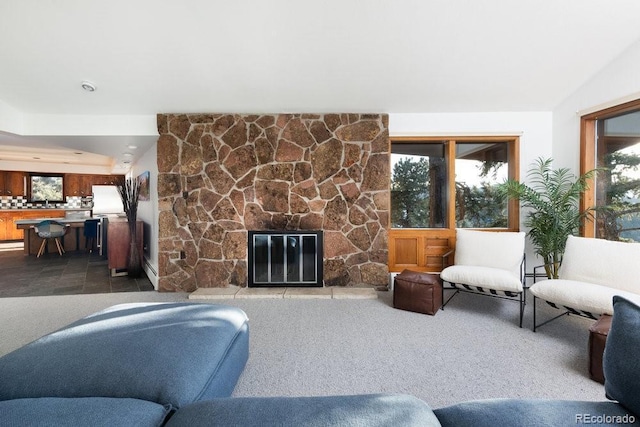 living area featuring lofted ceiling, a healthy amount of sunlight, and a stone fireplace