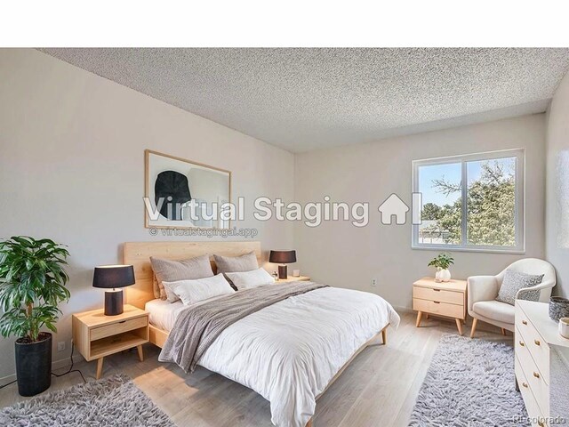 bedroom with a textured ceiling and light wood-type flooring