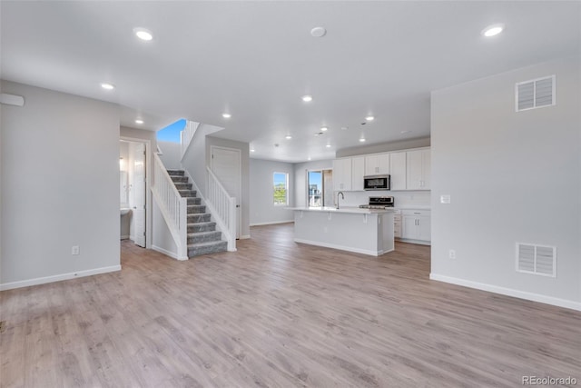 unfurnished living room featuring sink and light wood-type flooring