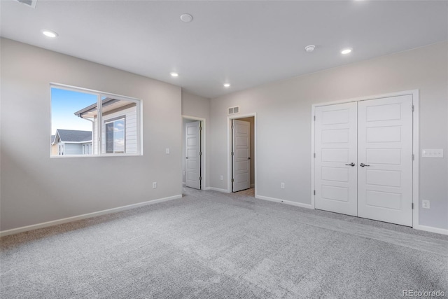 unfurnished bedroom with light colored carpet and a closet