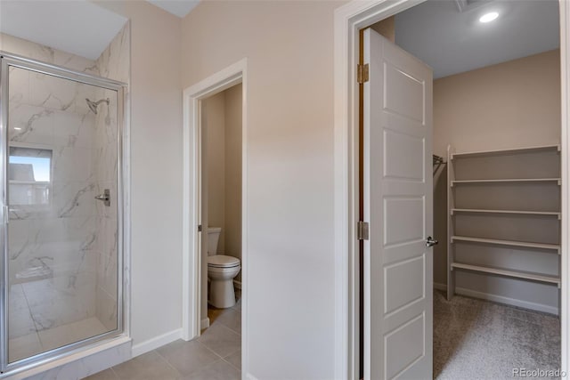 bathroom with tile patterned flooring, a shower with shower door, and toilet