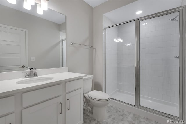 bathroom with toilet, vanity, and a shower with shower door