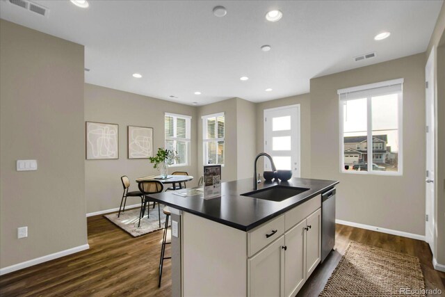 kitchen featuring sink, a center island with sink, stainless steel dishwasher, a healthy amount of sunlight, and white cabinets