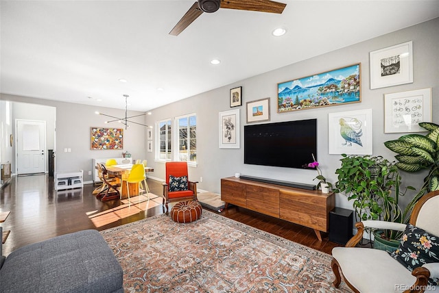 living room featuring ceiling fan with notable chandelier, recessed lighting, baseboards, and wood finished floors