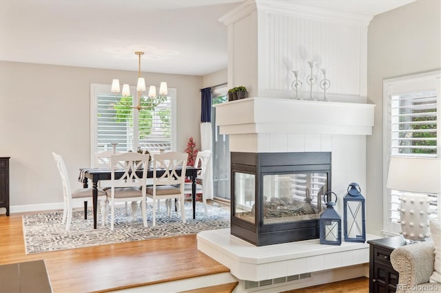 1449 Braewood Ave, Highlands Ranch, CO 80129 - living room with wood finished floors, healthy amount of natural light, a chandelier, and a tiled fireplace