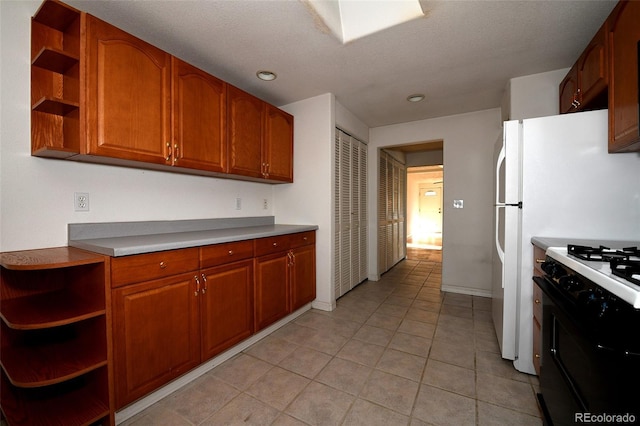 kitchen with light tile patterned floors, white gas range oven, and a textured ceiling