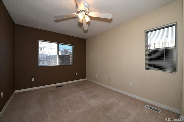 unfurnished room featuring carpet flooring, ceiling fan, a healthy amount of sunlight, and a textured ceiling