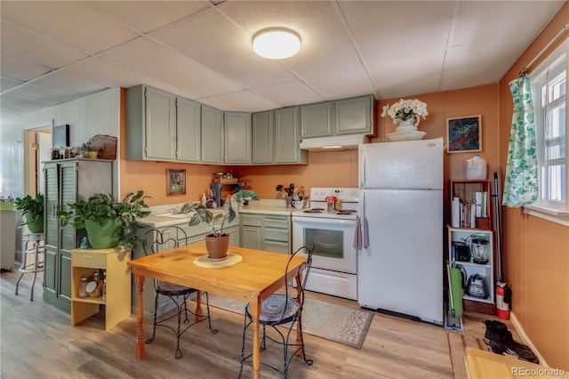 kitchen featuring a paneled ceiling, white appliances, light countertops, under cabinet range hood, and light wood-style floors