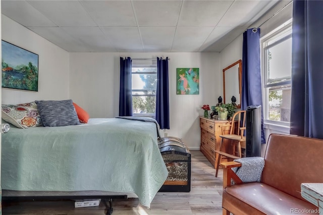bedroom with light wood-type flooring and a paneled ceiling