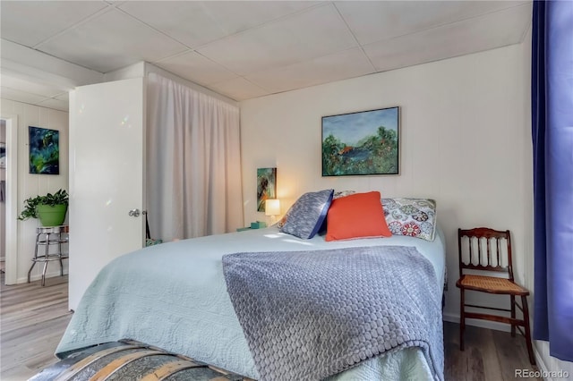 bedroom with a paneled ceiling and wood finished floors