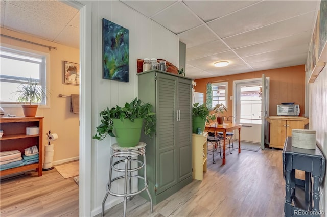 interior space with green cabinetry, light wood-style flooring, and a drop ceiling