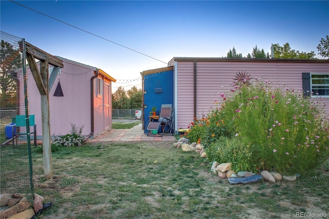 view of yard featuring a patio area, fence, and an outbuilding