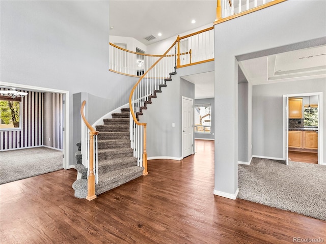 entryway with dark hardwood / wood-style floors and a towering ceiling