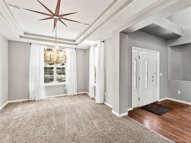 entryway featuring a chandelier, wood-type flooring, and a raised ceiling