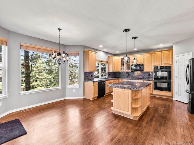 kitchen with hanging light fixtures, a center island, light brown cabinets, and black appliances