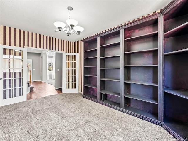 empty room featuring carpet floors, french doors, and a chandelier