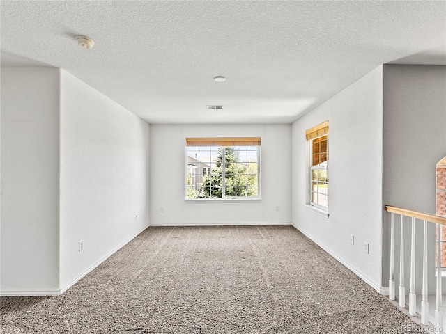 carpeted empty room with a textured ceiling